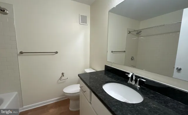 a bathroom with a granite countertop sink toilet a mirror and shower