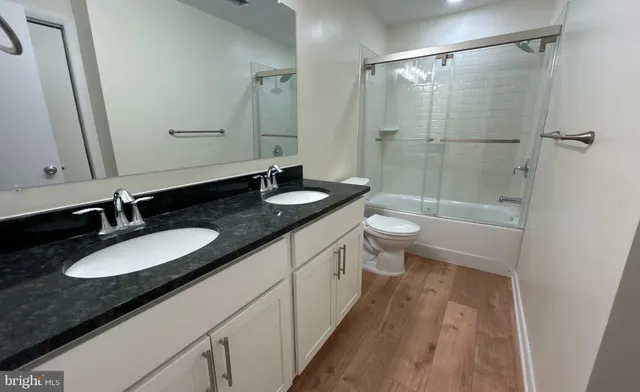 a bathroom with a granite countertop sink a toilet a mirror and shower