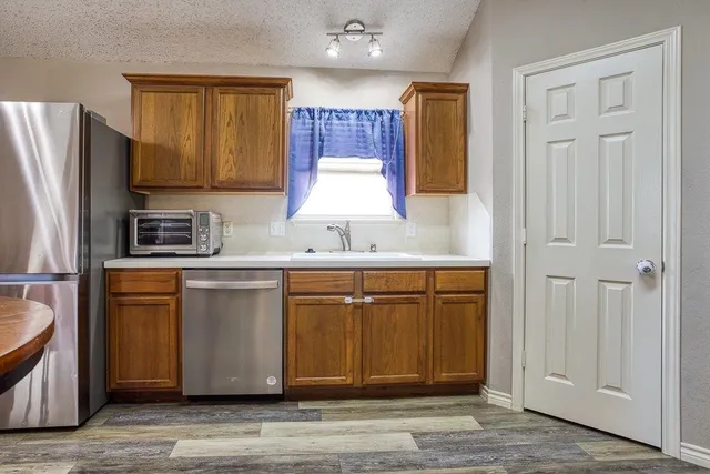 a kitchen with granite countertop wooden cabinets a sink a stove a refrigerator and island