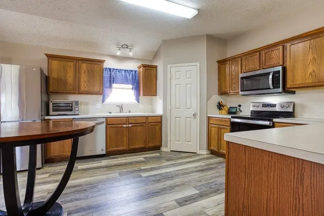a kitchen with granite countertop wooden floors stainless steel appliances a sink and a window