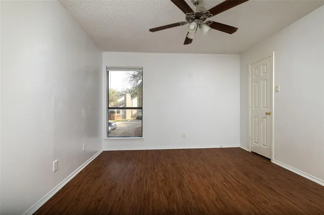 an empty room with wooden floor chandelier fan and windows
