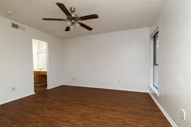 an empty room with wooden floor a ceiling fan and windows