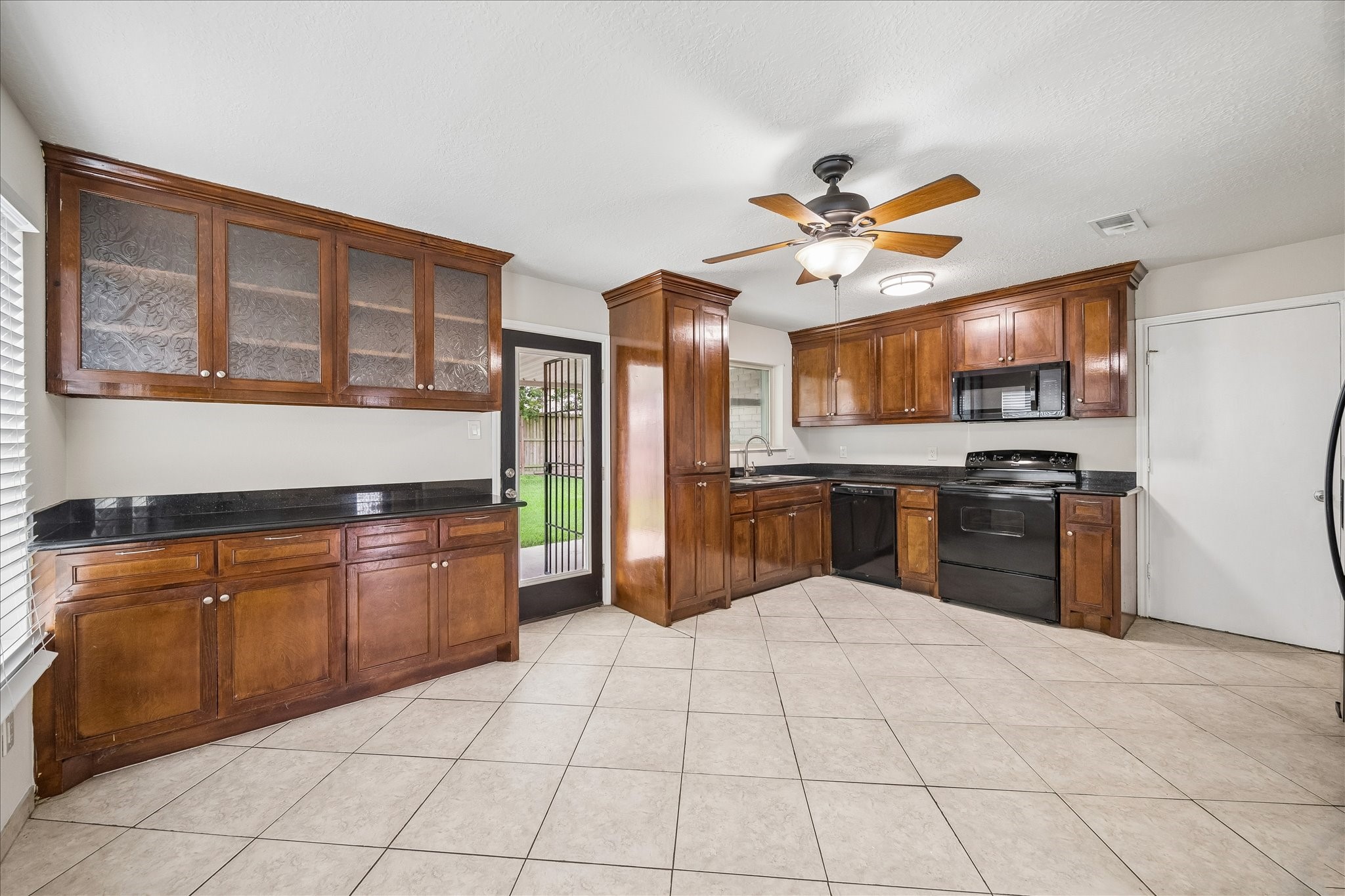 10411 Goodrum Road Houston, TX 77041 - Photo 8 of 25 Kitchen is very spacious with custom wood cabinetry, granite countertops and black appliances. This kitchen accommodates your dining area too