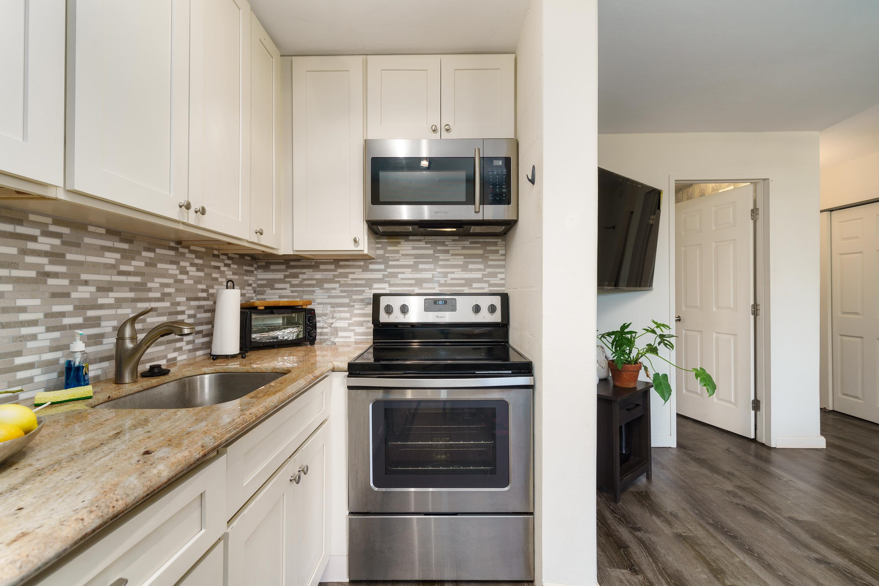 3660 Lower Honoapiilani Road, Unit 111 Lahaina, HI 96761 - Photo 3 of 28 a kitchen with granite countertop a stove and cabinets