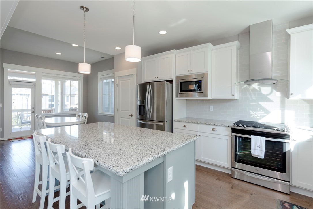 762 Lyons Avenue Northeast Renton, WA 98059 - Photo 4 of 33 a kitchen with stainless steel appliances granite countertop a stove a sink a microwave a refrigerator white cabinets and a refrigerator
