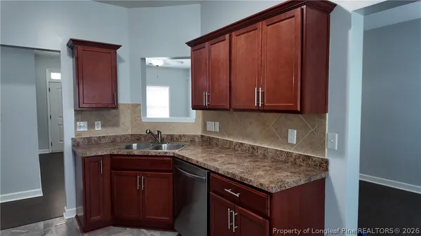 a kitchen with granite countertop a sink cabinets and stainless steel appliances