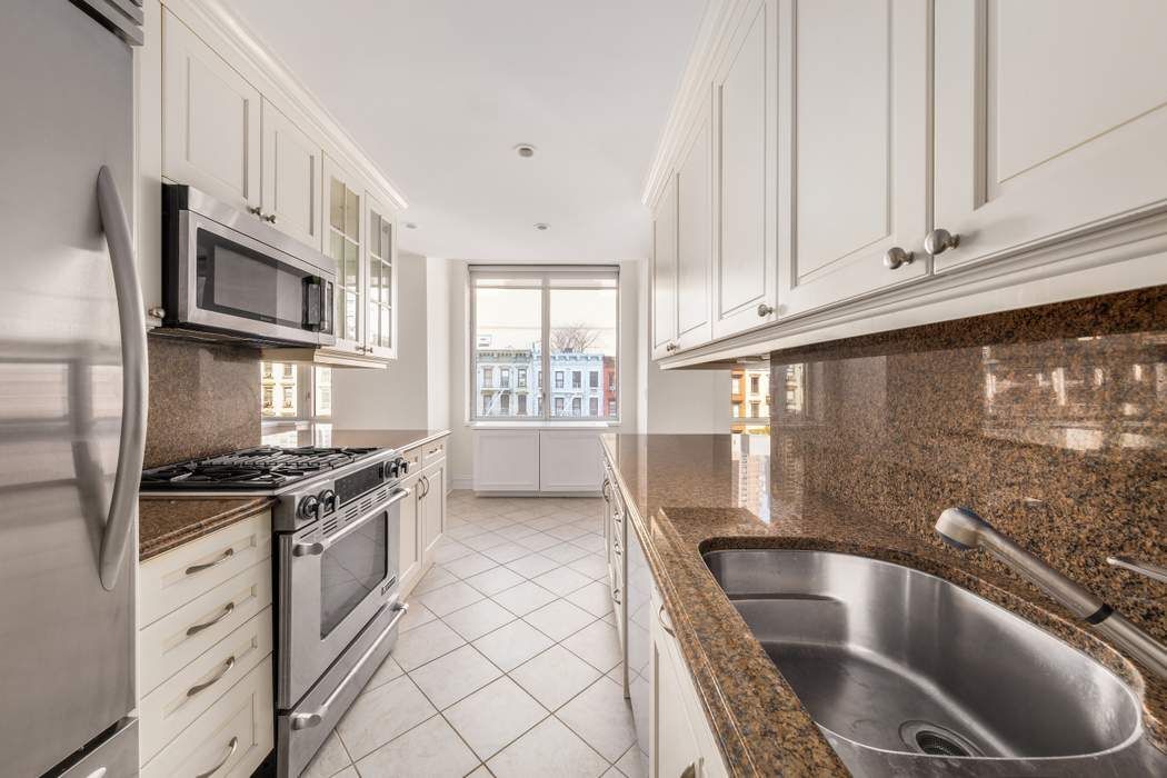 401 East 60th Street, Unit 4C Manhattan, NY 10022 - Photo 21 of 28 a kitchen with granite countertop a stove sink and cabinets