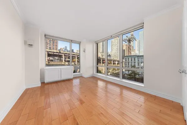 a view of an empty room with a window and wooden floor