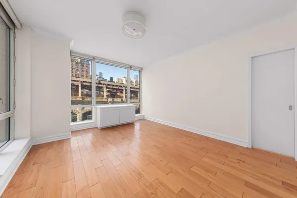 a view of an empty room with a window and wooden floor