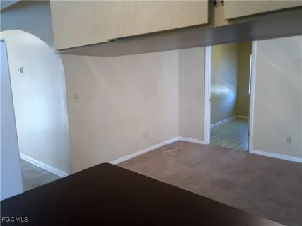 a view of an empty room with a chandelier fan and a fireplace
