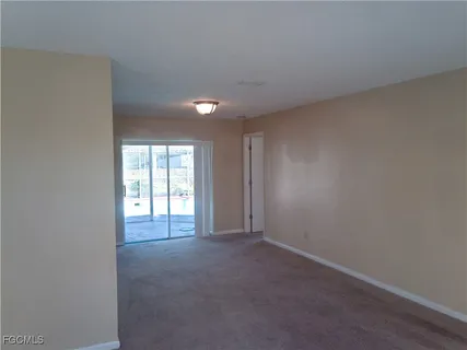 an empty room with a window and chandelier fan