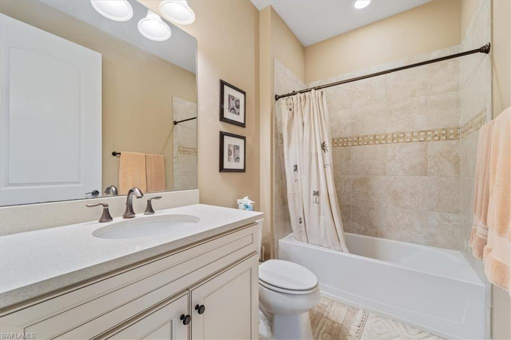 9418 Greyhawk Trail Naples, FL 34120 - Photo 12 of 34 a bathroom with a sink a toilet a mirror a vanity and shower