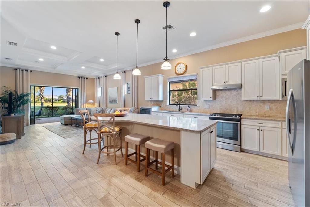 9418 Greyhawk Trail Naples, FL 34120 - Photo 7 of 34 a open kitchen with stainless steel appliances granite countertop a stove top oven a large island with white cabinets and wooden floor
