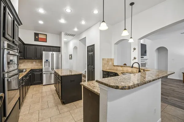 a large kitchen with stainless steel appliances granite countertop a sink a stove and a refrigerator