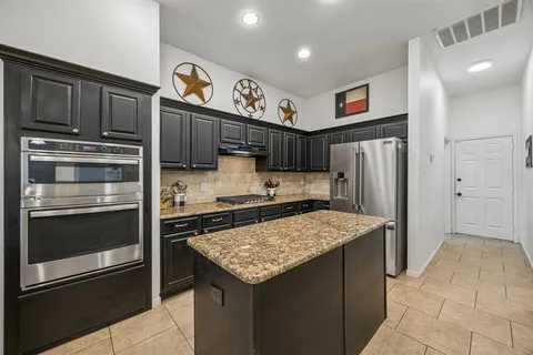 a kitchen with stainless steel appliances granite countertop a refrigerator stove and sink