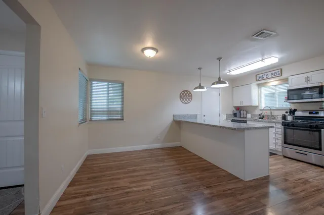 a kitchen with wooden floors and white cabinets