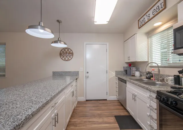 a kitchen with stainless steel appliances granite countertop a sink a stove and a wooden floors