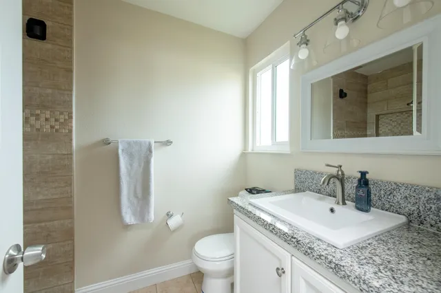 a bathroom with a granite countertop sink a toilet and a mirror
