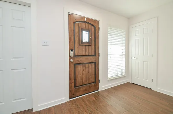 an empty room with wooden floor cabinet and windows