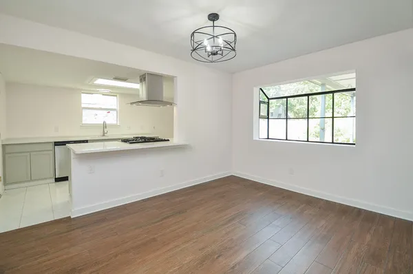 an empty room with wooden floor cabinet and windows