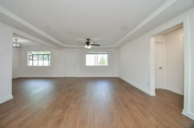 an empty room with wooden floor and windows