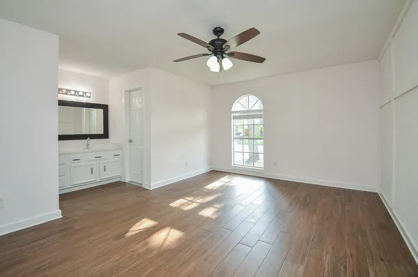 an empty room with windows and a ceiling fan