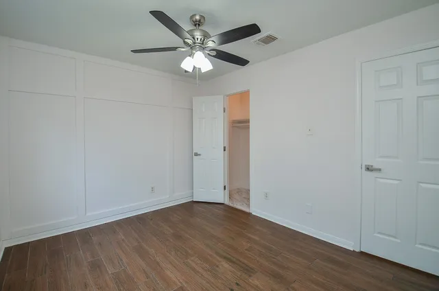 an empty room with wooden floor and ceiling fan