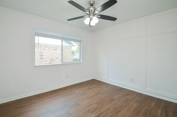an empty room with wooden floor ceiling fan and windows