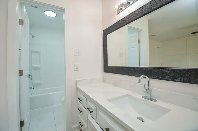 a bathroom with a bathtub shower sink vanity and mirror