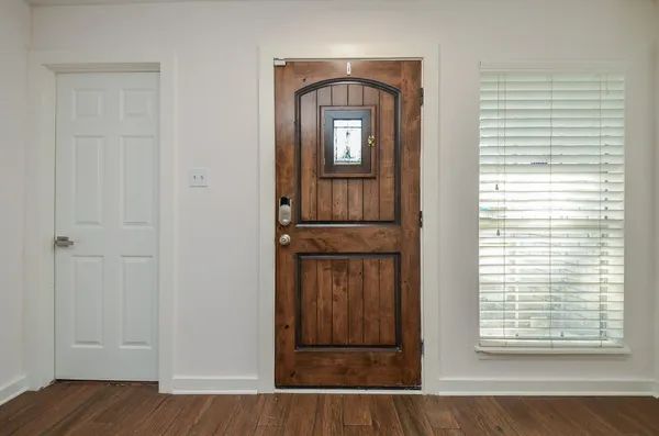 an empty room with wooden floor kitchen view and windows