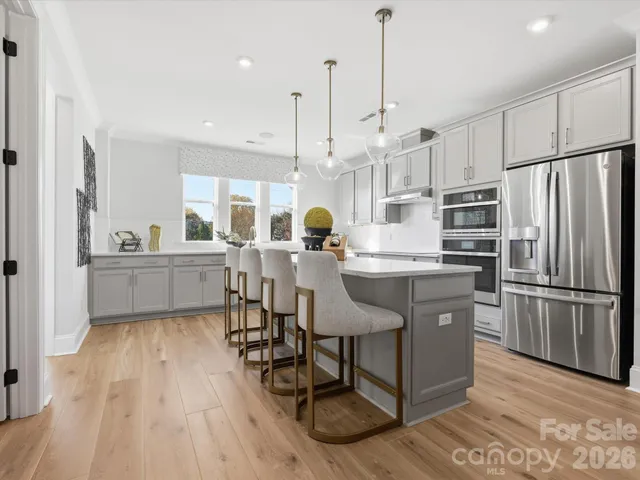 a kitchen with stainless steel appliances a sink a stove a refrigerator a center island and wooden floor