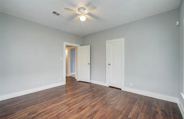 an empty room with wooden floor and ceiling fan