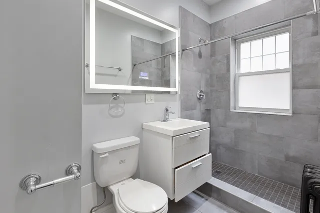 a bathroom with a granite countertop toilet sink and mirror