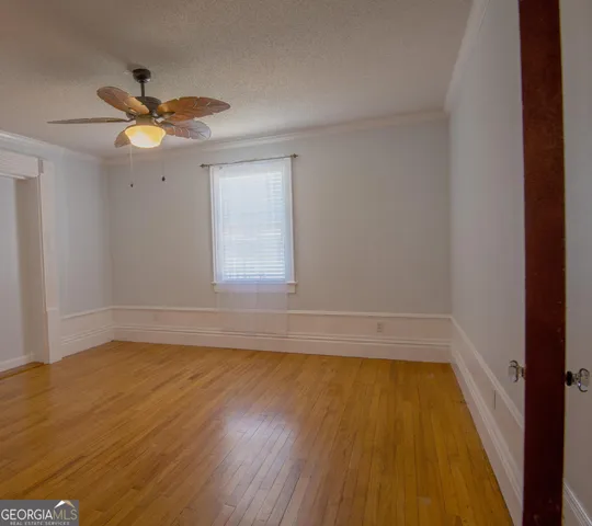 a view of an empty room with window and wooden floor