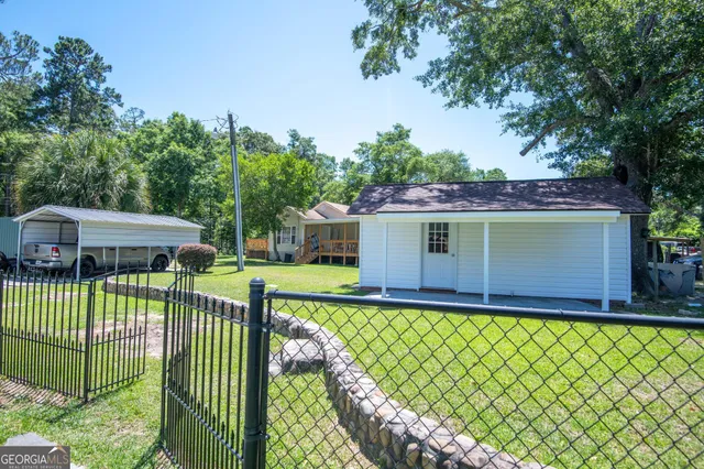 a view of a backyard with plants and large tree
