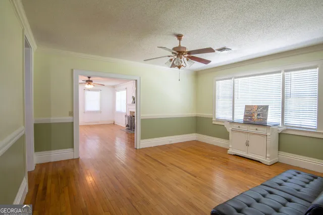 a view of an empty room with window and wooden floor