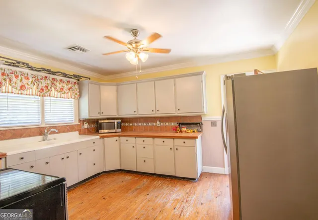 a kitchen with stainless steel appliances a sink cabinets and wooden floor