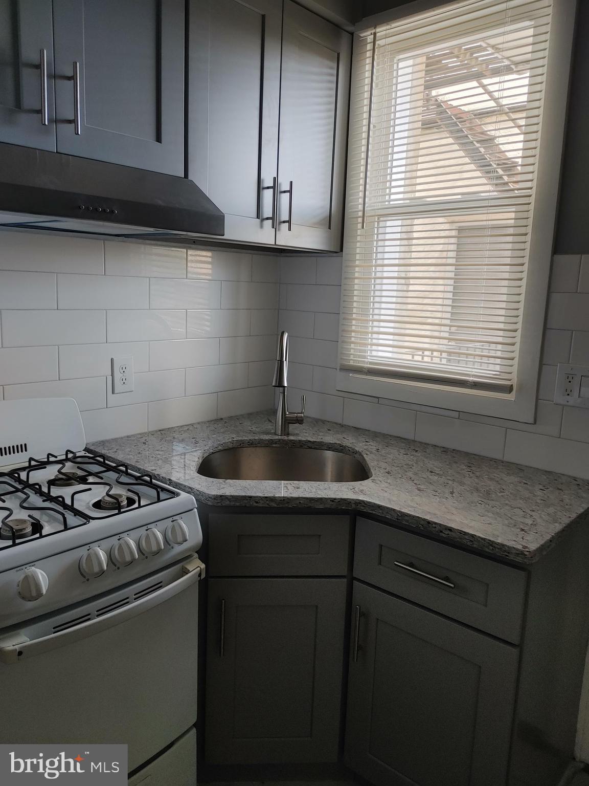 5917 Spruce Street, Unit 1 Philadelphia, PA 19139 - Photo 11 of 15 a kitchen with granite countertop a sink stove and cabinets