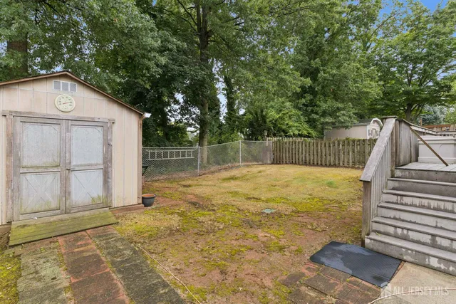 a view of backyard with small cabin and wooden fence