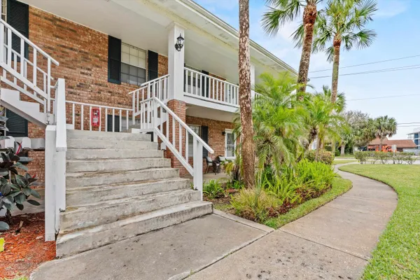 a view of a brick house with plants and a small yard