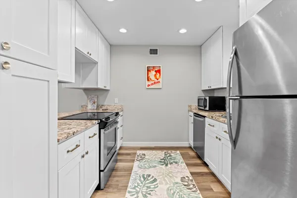 a kitchen with stainless steel appliances granite countertop a refrigerator a stove and a sink