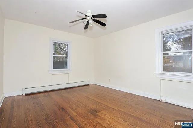 an empty room with wooden floor fan and windows