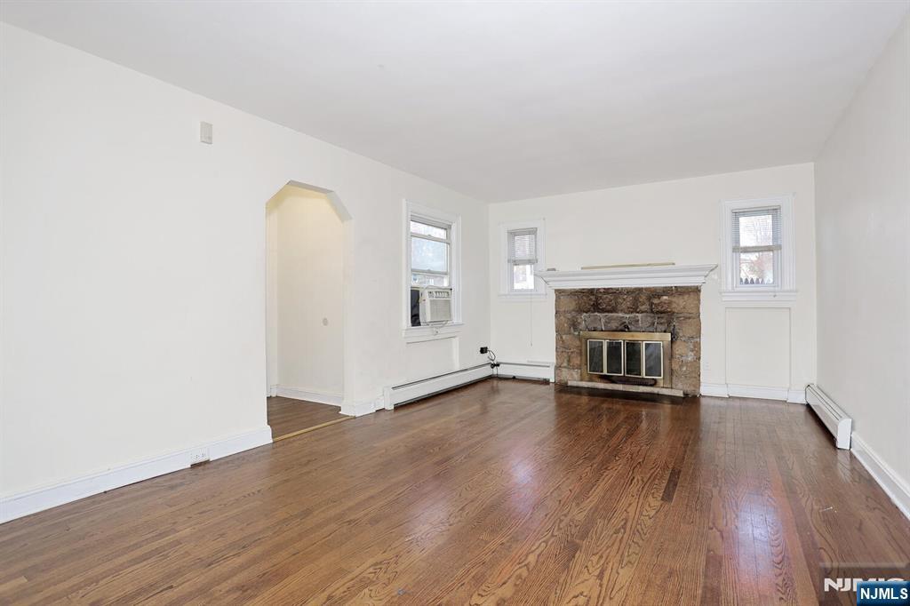 325 New Bridge Road Bergenfield, NJ 07621 - Photo 4 of 50 an empty room with wooden floor and fireplace