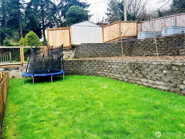 a view of a backyard with wooden fence and a bench