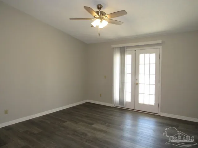 a view of an empty room with window and wooden floor