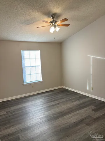 an empty room with wooden floor chandelier fan and windows