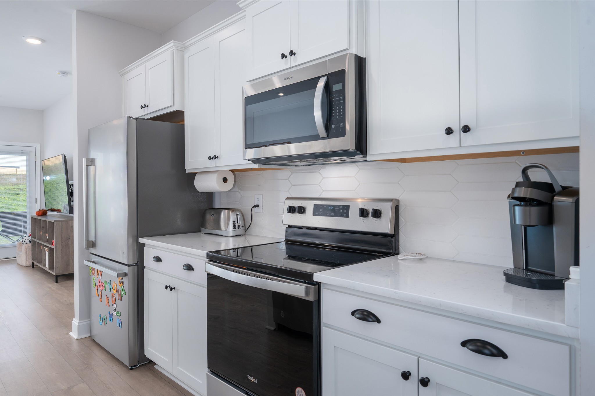 1060 June Wilde Ridge Spring Hill, TN 37174 - Photo 7 of 43 a kitchen with stainless steel appliances white cabinets and a stove a refrigerator with wooden floor