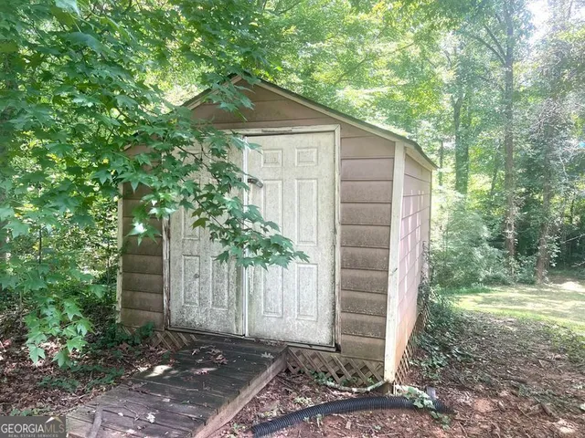 a backyard of a house with plants and large tree
