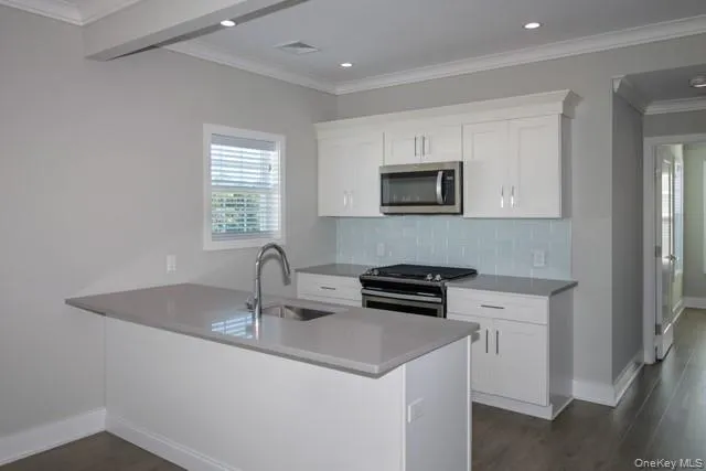 a kitchen with stainless steel appliances a sink a stove a microwave a refrigerator a counter space and cabinets