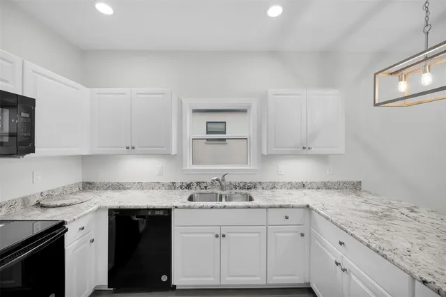 a kitchen with granite countertop stainless steel appliances white cabinets granite counter tops and a wooden floors